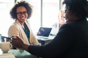 two black women smiling at a phone